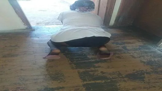 Köy evinde başörtülü bir kadın yeri siliyor